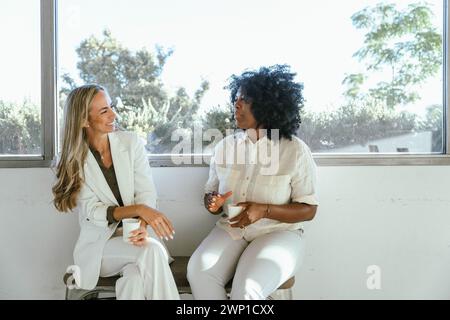 Two colleagues drinking coffee while having a break from work at the office. Business concept. Stock Photo