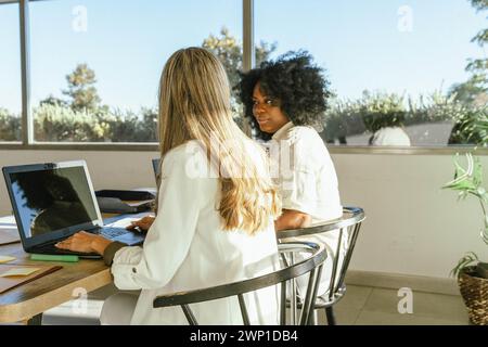 Two female colleagues talking while working in the office. Business concept. Stock Photo