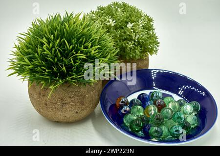 Two small rounded green artificial plants next to a group of glass marbles Stock Photo