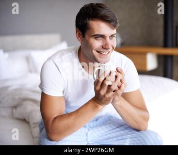 Man, bedroom and morning coffee sitting and thinking, weekend off in apartment to relax with attractive male person. Casual and holiday or home Stock Photo