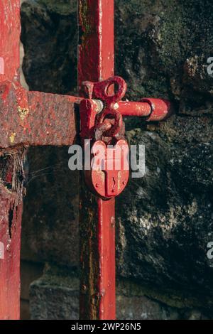 An old red padlock on a metal  gate Stock Photo