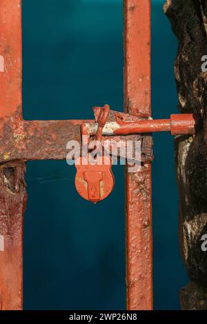 An old red padlock on a metal  gate Stock Photo