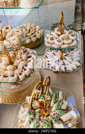 Vertical photo an elegant assortment of Middle Eastern pastries presented on golden tiered trays, showcasing traditional designs and textures. Food an Stock Photo