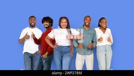 Five cheerful young individuals from diverse ethnic backgrounds giving thumbs up Stock Photo