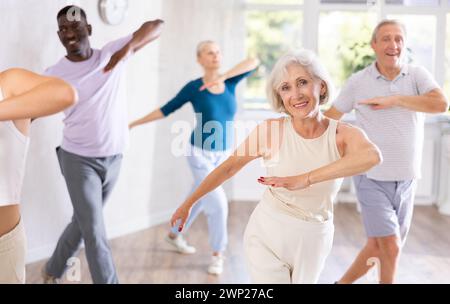 Elderly woman practicing vigorous dance during group class Stock Photo