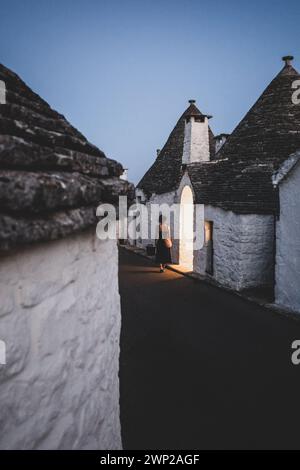 ITALY, PUGLIA, ALBEROBELLO: Street views of the trulli of Alberobello at sunset. The city of Alberobello is famously known as the capital of the trulli, the characteristic stone buildings with a conical roof that never like others, represent in the imagination, the entire Puglia region. It was born as a basic building for agricultural needs, the trulli were in fact used as temporary shelters, deposits, stables, and as the technique was refined, as homes. Stock Photo