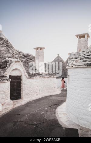 ITALY, PUGLIA, ALBEROBELLO: Street views of the trulli of Alberobello at sunset. The city of Alberobello is famously known as the capital of the trulli, the characteristic stone buildings with a conical roof that never like others, represent in the imagination, the entire Puglia region. It was born as a basic building for agricultural needs, the trulli were in fact used as temporary shelters, deposits, stables, and as the technique was refined, as homes. Stock Photo