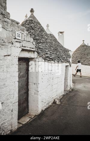 ITALY, PUGLIA, ALBEROBELLO: Street views of the trulli of Alberobello at sunset. The city of Alberobello is famously known as the capital of the trulli, the characteristic stone buildings with a conical roof that never like others, represent in the imagination, the entire Puglia region. It was born as a basic building for agricultural needs, the trulli were in fact used as temporary shelters, deposits, stables, and as the technique was refined, as homes. Stock Photo