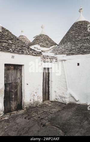 ITALY, PUGLIA, ALBEROBELLO: Street views of the trulli of Alberobello at sunset. The city of Alberobello is famously known as the capital of the trulli, the characteristic stone buildings with a conical roof that never like others, represent in the imagination, the entire Puglia region. It was born as a basic building for agricultural needs, the trulli were in fact used as temporary shelters, deposits, stables, and as the technique was refined, as homes. Stock Photo