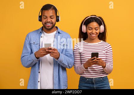 Smiling Black Couple Wearing Wireless Headphones Using Modern Smartphones Stock Photo