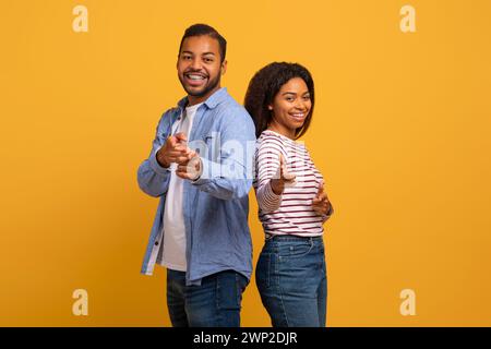 Cheerful young black couple playfully pointing at the camera with confident smiles Stock Photo