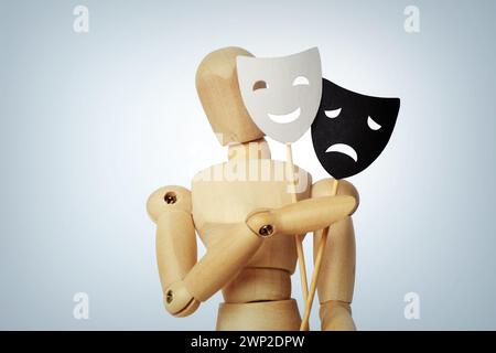 Wooden mannequin with two masks showing different emotions - Concept of psychology, mood change and bipolar disorder Stock Photo