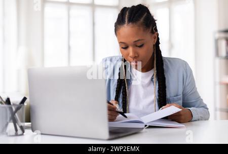Dedicated female student focusing on her studies with laptop Stock Photo
