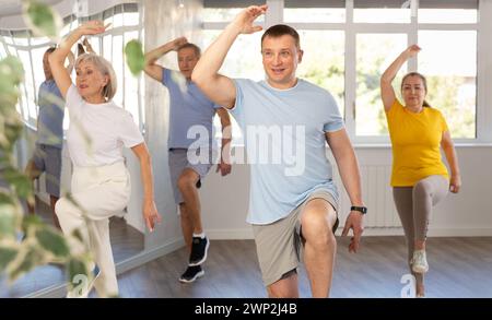Positive instructor leading zumba class for seniors in fitness studio Stock Photo