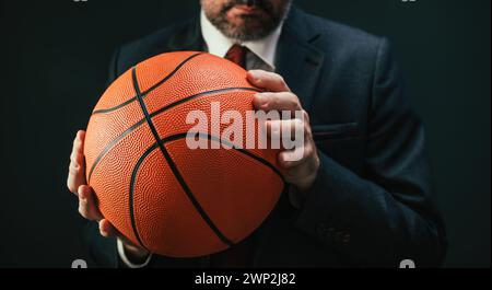 Basketball coach in elegant business suit holding the ball, selective focus Stock Photo