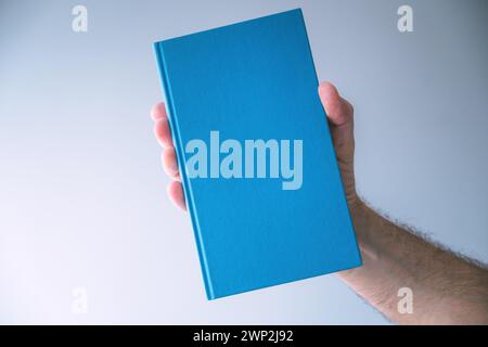 Blue hardcover book mockup, man holding book, selective focus Stock Photo