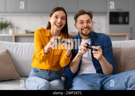 Joyful couple playing video games together on the couch Stock Photo