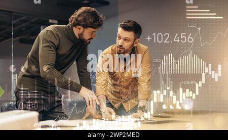 Two male colleagues in casual attire discuss a project over a table in a contemporary office Stock Photo