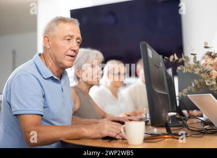 Old man learning computer programs in training room Stock Photo