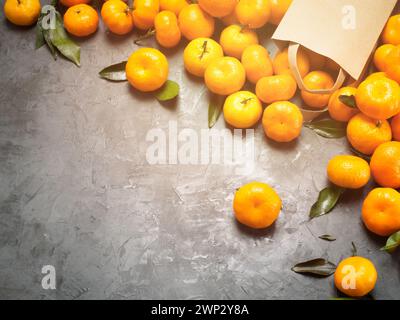 Flat lay of craft bag with tangerines on the gray concrete background with a glare of sunlight, vignette and copy space. Stock Photo