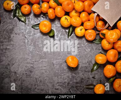 Flat lay of craft bag with tangerines on the gray concrete background, vignette and copy space. Harsh light and shadows. Stock Photo