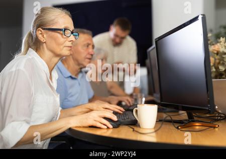 Old woman learning computer programs in training room Stock Photo