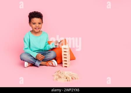 Full length photo of adorable little boy play wooden bricks wear trendy aquamarine garment isolated on pink color background Stock Photo