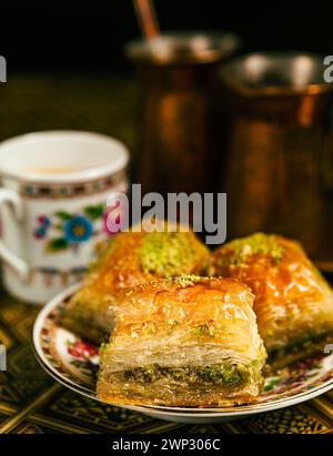 Still life with hot oriental coffee brewed in cezve. On the Arabic table is a small coffee cup and delicious honey baklava with pistachios on a saucer Stock Photo