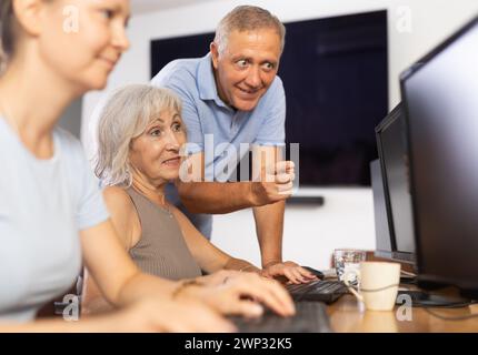 Old woman learning computer programs with teacher in training room Stock Photo