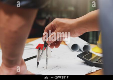 Engineer or architect using divider compass tools on blueprint in office on site. Stock Photo