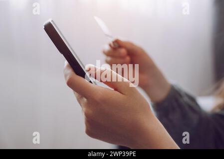 Close up of female hands holding credit card and smartphone, young woman paying online, using banking service, entering information, shopping, orderin Stock Photo