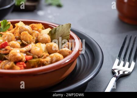 Close up. Ropa vieja, typical Canarian dish of chickpeas stew on earthenware casserole on dark base. Stock Photo