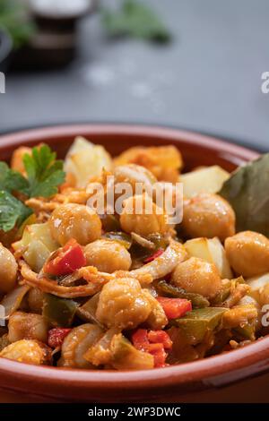 Ropa vieja, typical Canarian dish of chickpeas stew on earthenware casserole on dark table. Close up. Vertical format. Stock Photo