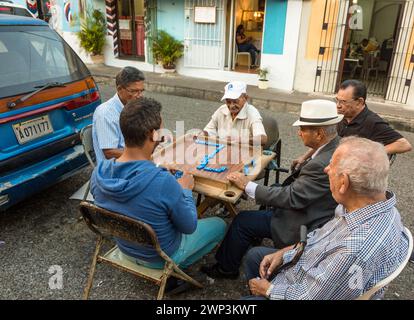 Dominican men playing dominoes on the in the street in the old Colonial City of Santo Domingo, Dominican Republic.  Dominos is the unofficial national Stock Photo