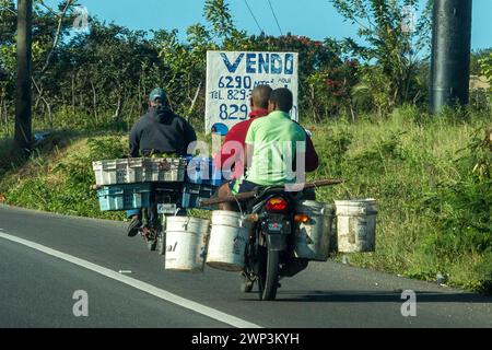 Men carry goods on their motorcycles in homemade panniers and buckets in the Dominican Republic. Stock Photo