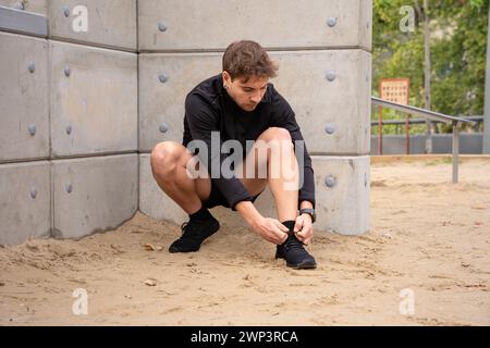 Young caucasian athlete lacing up his sneakers before working out. Stock Photo