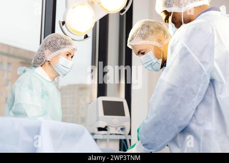 A group of doctors wearing masks are standing together around a table. Stock Photo