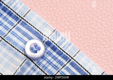 Button on plaid blue shirt pink background Stock Photo