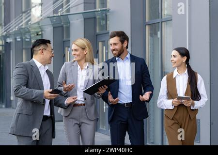 Group of happy business professionals in a casual meeting outside an office. They are discussing work and sharing a laugh. Stock Photo