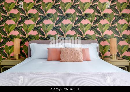 Bedroom with pink and green accent colors and tropical wallpaper theme Stock Photo