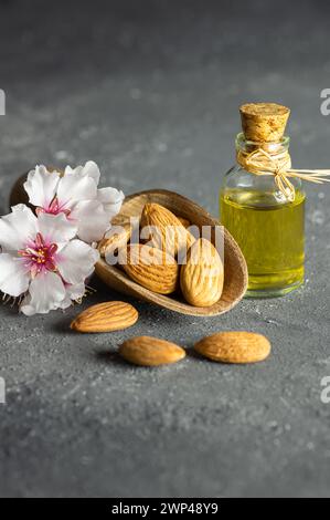 Glass bottle of Almond oil and almond nuts , almonds with almond tree flowers on table. Almond background concept with copy space Stock Photo