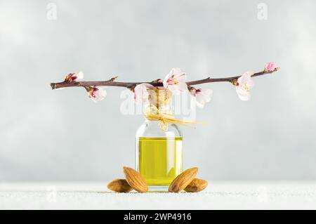 Glass bottle of Almond oil and almond nuts , almonds with almond tree flowers on table. Almond background concept with copy space Stock Photo