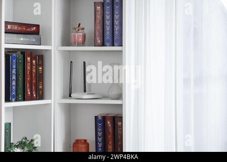 Bookshelf with modern wi-fi router in room Stock Photo