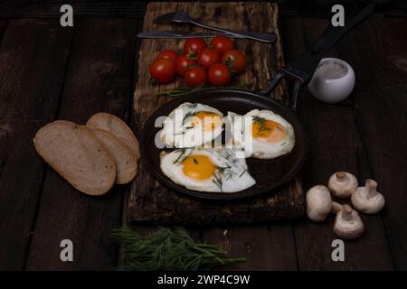 Fried eggs in a pan with vegetables and herbs on a black background Stock Photo