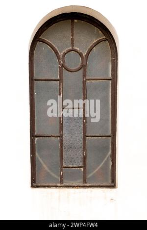 vintage brown wooden window in white wall of old church, metallic fence and gate Stock Photo