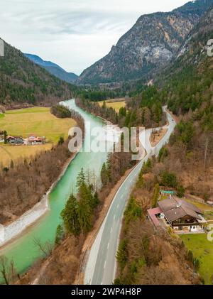 Aerial view of a winding Saalach river next to a road with surrounding forest and mountains under a cloudy sky, Bad Reichenhall, Bavaria, Germany Stock Photo