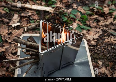Closeup shot of a survival metal stove with burning flames and wood, demonstrating outdoor survival skills and the ability to ignite fire in adverse c Stock Photo
