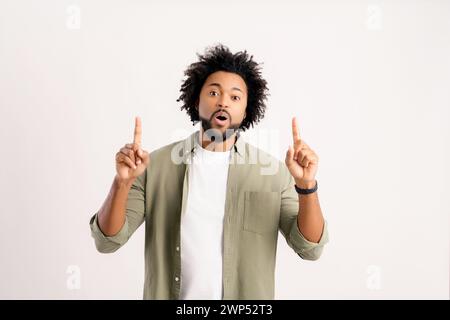 Just look here. Shocked African man points palms of both hands away at copy space, isolated on white, astonished black guy draws attention to advertising, mockup Stock Photo