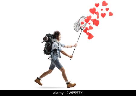 Full length profile shot of a young man with a backpack running and catching hearts with a net isolated on white background Stock Photo