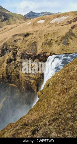 Gorgeous nordic skgafoss waterfall with water stream pouring down off hilltop edges, icelandic cascade with river flow falling. Beautiful nordic wilderness presenting natural landscape. Stock Photo
